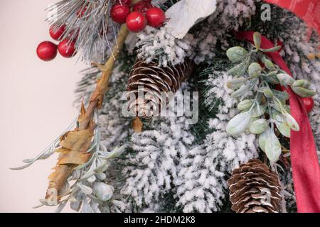 Weihnachtliche Dekoration mit Schnee, Evergreens, Kegelbällen und Feiertagsmotiven. Goldenes und rotes Band. Frohes neues Jahr und frohe Weihnachten. Stockfoto