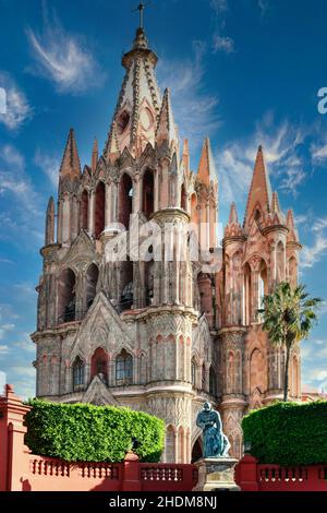 Blick auf die spektakuläre pinke neugotische Kathedrale Parroquia de San Miguel Arcangel aus dem 17th. Jahrhundert mit der Statue Fray Juan in San Miguel de Allende, MX Stockfoto