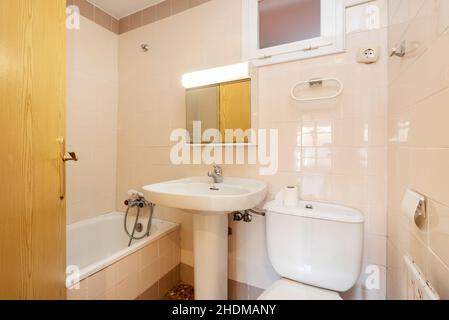 Herkömmliche Toilette mit weißen Accessoires und cremefarbenen Wänden Stockfoto