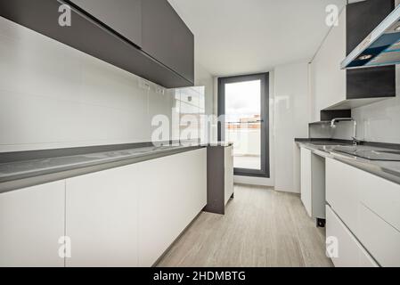 Neu installierte Küche mit weißen und grauen Möbeln und Zugang zu einer Terrasse im Dachgeschoss Stockfoto