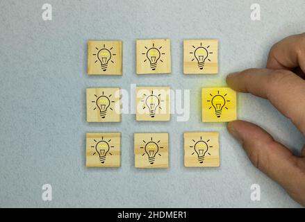 Innovations- und Lösungskonzept, Holzblöcke mit dem gelben Glühbirnensymbol auf blauem Hintergrund. Stockfoto