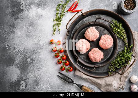 Rohe Burger-Koteletts aus biologischem Fleisch, auf grauem Steintisch-Hintergrund, Draufsicht flach liegend, mit Platz für Text Stockfoto
