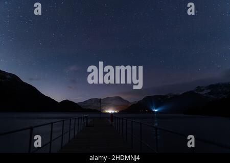 Ein Blick auf den Nachthimmel vom Steamer-Steg der Aira Force mit dem Schein eines Autolichts, das durch die Bäume leuchtet. Stockfoto