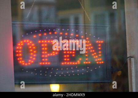 Nahaufnahme kreisförmige rote LED offen Schild an einer Glastür Stockfoto