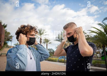 Zwei Jungen draußen tragen chirurgische Masken, um sich während der Covid-19-Pandemie zu schützen. Nutzung der Gesichtsmask im Freien während Stockfoto