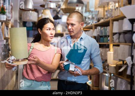 Mann und Frau entscheiden sich für eine neue Tischleuchte für ihr Zuhause im Geschäft Stockfoto