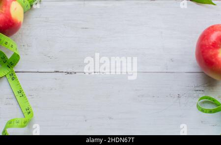 Gewichtsverlust Konzept, Apfel und Maßband auf der leichten Holzoberfläche Stockfoto