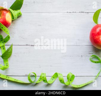 Gewichtsverlust Konzept, Apfel und Maßband auf der leichten Holzoberfläche Stockfoto