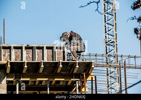 Ein Schweißer bereitet aus der Bewehrung einen Rahmen vor, um Beton in den tragenden Träger eines Wohngebäudes zu gießen. Stockfoto