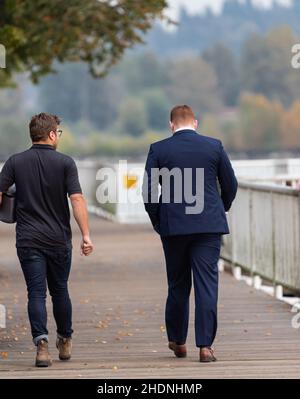 Zwei Freunde zu Fuß. Zwei gutaussehende, lässige, trendige junge Männer, 2 Freunde, in einem Stadtpark, die gemeinsam spazieren und plaudern. Straßenansicht, Reisefoto, Stockfoto