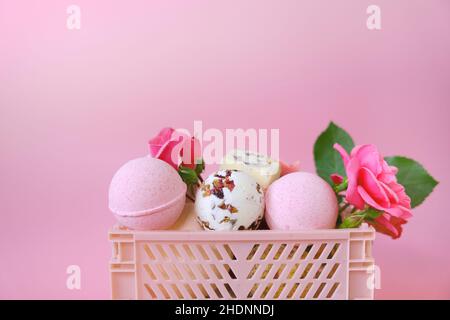 Badebomben und Trüffel mit Rosenblättern in einer Schachtel auf rosa Hintergrund.Badebomben mit Rosenextrakt.Schönheit und Aromatherapie. Blumenbad Bombs.Organic Stockfoto