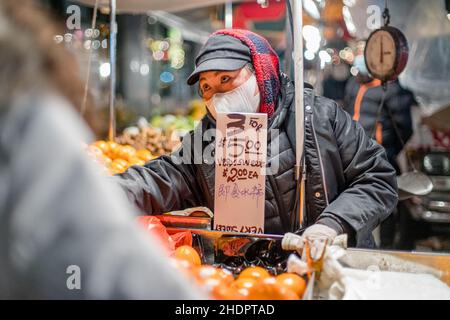New York, USA. 27th Dez 2021. Während der COVID-19 Pandemie-Omicron-Welle trägt der Obstmarktverkäufer Gesichtsmaske, während er in New York City in Chinatown arbeitet. (Bild: © Shawn Goldberg/SOPA Images via ZUMA Press Wire) Stockfoto
