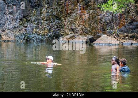 Airlie Beach, Queensland, Australien - Januar 2022: Menschen schwimmen im Wasser unter einem trockenen Wasserfall bei Cedar Falls Stockfoto