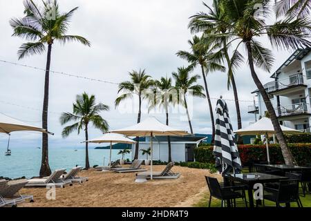 Airlie Beach, Queensland, Australien - Januar 2022: Der Strand des Luxus-Resort-Hotels am Meer mit Sonnenschirmen und Gartenmöbeln vor dem Hotel Stockfoto