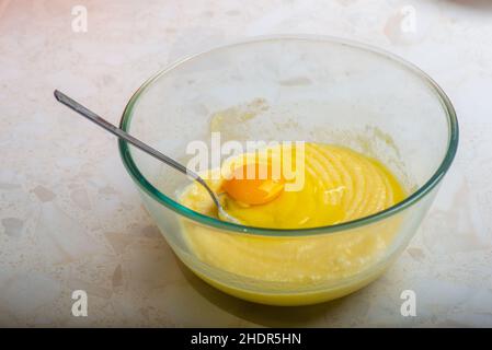 Ein Ei für den Kuchen in eine Tasse mit Zutaten geben Stockfoto