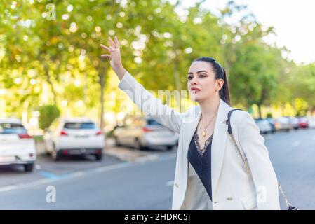 Junge Frau in weißer Jacke, die ein Taxi fordert Stockfoto