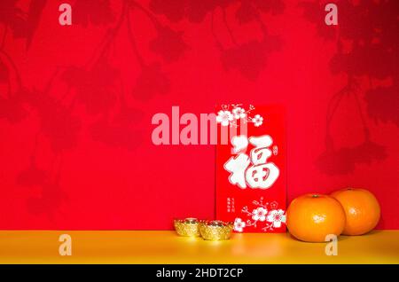 Rotes Umschlagpaket oder ang bao (Wort bedeuten Reichtum) legt mit Orangen und Barren mit Schatten der Pfirsichblüte auf gelben und roten Glitzerpapier Hintergrund Stockfoto