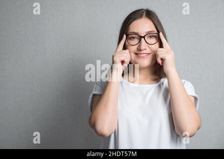 Brunette Frau hält Brille mit zwei Händen auf dem Nasenrücken Stockfoto