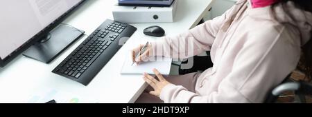 Frau im Rollstuhl arbeitet am Computer am Arbeitsplatz Stockfoto