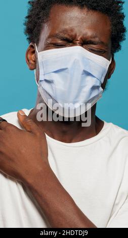 Verängstigte Person mit Gesichtsmaske, die gegen Coronavirus geimpft wird. Hände des Arztes mit Spritze, die jungen Mann mit Schutzmaske impfen. Erwachsene Angst vor Nadel und Impfung. Stockfoto