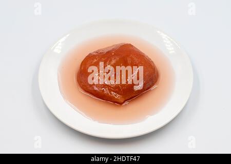 Quitte-Dessert mit Sirup auf weißem Hintergrund. Traditionelle Köstlichkeiten der mediterranen Küche. Türkisches Ramadan-Dessert. Horizontale Ansicht. Nahaufnahme Stockfoto