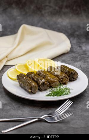 Gefüllte Traubenblätter mit Olivenöl auf dunklem Grund. Traditionelle türkische Küche Delikatessen. Köstlicher Dolma (Yaprak-Karma). Vertikale Ansicht. Schließen Stockfoto