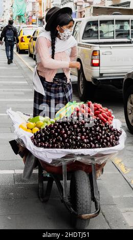 Cuenca, Ecuador, 24. Dez 2021 - eine Frau verkauft Kirschen und Früchte von einer Schubkarre. Stockfoto