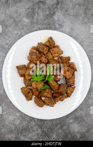 Gebratene Leberwürfel auf dunklem Grund. Türkische Traditionelle Küche Arnavut Cigeri. Draufsicht. Nahaufnahme Stockfoto