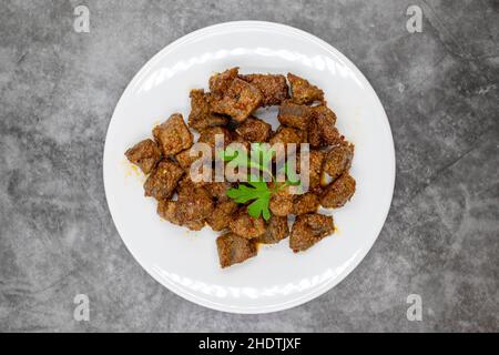 Gebratene Leberwürfel auf dunklem Grund. Türkische Traditionelle Küche Arnavut Cigeri. Draufsicht. Nahaufnahme Stockfoto