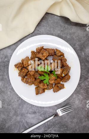 Gebratene Leberwürfel auf dunklem Grund. Türkische Traditionelle Küche Arnavut Cigeri. Draufsicht. Nahaufnahme Stockfoto