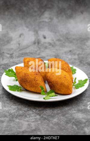 Kibbeh auf dunklem Hintergrund. Kibbeh ist ein beliebtes Gericht in der nahöstlichen Küche. Gefüllte Fleischbällchen Essen, Falafel, icli Kofta, Quibe. Vertikale Ansicht. Cl Stockfoto