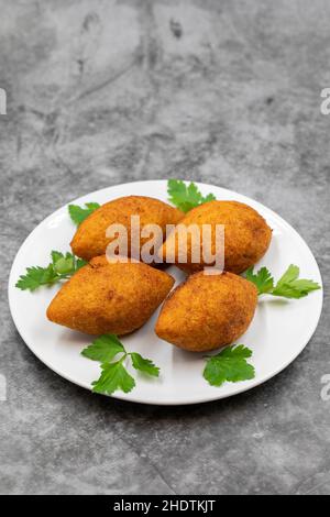 Kibbeh auf dunklem Hintergrund. Kibbeh ist ein beliebtes Gericht in der nahöstlichen Küche. Gefüllte Fleischbällchen Essen, Falafel, icli Kofta, Quibe. Vertikale Ansicht. Cl Stockfoto