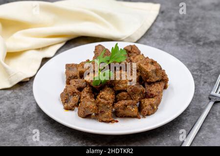 Gebratene Leberwürfel auf dunklem Grund. Türkische Traditionelle Küche Arnavut Cigeri. Horizontale Ansicht. Nahaufnahme Stockfoto