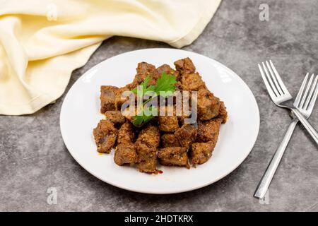 Gebratene Leberwürfel auf dunklem Grund. Türkische Traditionelle Küche Arnavut Cigeri. Horizontale Ansicht. Nahaufnahme Stockfoto