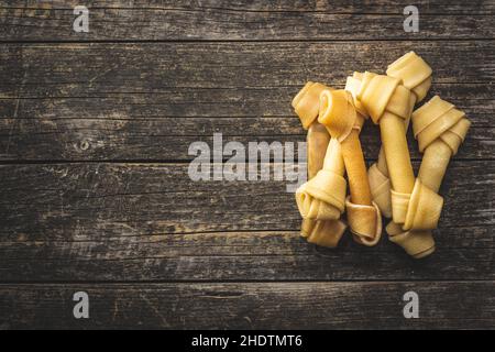 Delikatesse für Hunde. Kauknochen für Hund auf Holztisch. Draufsicht. Stockfoto