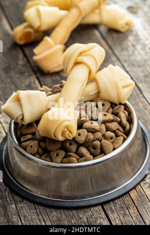 Delikatesse für Hunde. Kauknochen und getrocknetes Futter für Hund auf Holztisch. Stockfoto