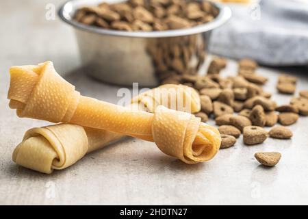 Delikatesse für Hunde. Kauknochen und getrocknetes Futter für Hund auf grauem Hintergrund. Stockfoto