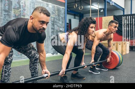 Gemischte Teams, die Gewichte im Fitnessstudio heben Stockfoto