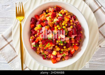 Vinegret, russische Vinaigrette, Salat aus gewürfeltem gekochtem Gemüse, rote Rüben, Kartoffeln, Karotten, gehackte Zwiebeln, gebeizte Gurken, Grüne Erbsen in einem weißen bo Stockfoto