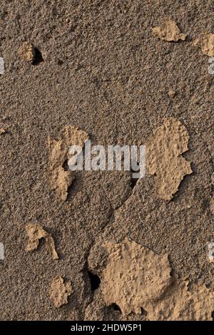 Alte Mauer mit zerbröckelndem und ruinierten gelben Putz, senkrechte Ansicht Stockfoto