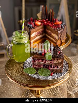 Leckere geschichtete Schokoladenkuchen mit Beeren serviert mit Minzlemonade Stockfoto
