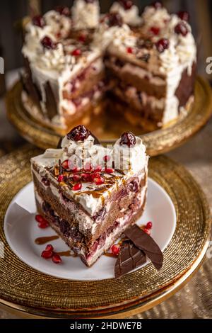 Schwarzer Waldkuchen mit Schlagsahne und Kirschen und Granatapfelkernen Stockfoto
