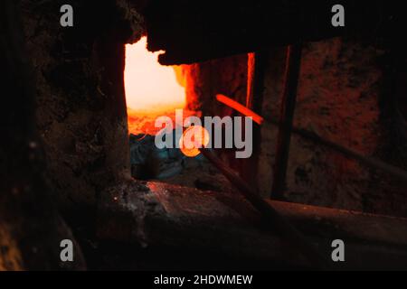 Nahaufnahme eines pruduzierenden bösen Auges oder Amuletts in der Nähe des Ofens. Das Amulett ist rot, weil es brennt. Stockfoto