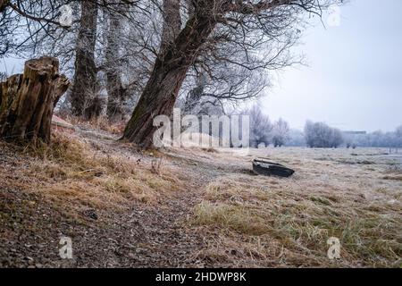 Ein hölzerner Fischerboot, der in gefrorenem Wasser am Ufer des Donau-Zufluss ausgezogen wurde. Stockfoto