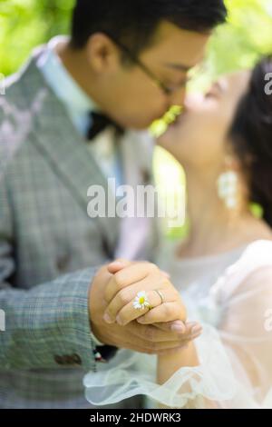 Vertikale Nahaufnahme des verschwommenen küssenden Paares, das die Hände hält. Ausgewählter Fokus. Stockfoto