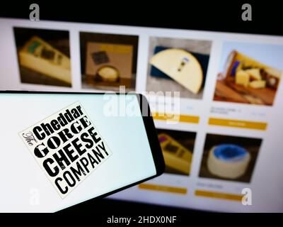 Mobiltelefon mit Logo des britischen Unternehmens The Cheddar Gorge Cheese Company Ltd auf dem Bildschirm vor der Website. Konzentrieren Sie sich auf die Mitte des Telefondisplays. Stockfoto