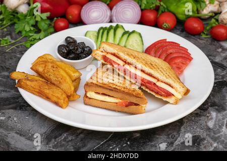 Toast mit Cheddar-Käse, Wurst und Tomaten mit pommes Frites und Salat auf Marmortisch Stockfoto