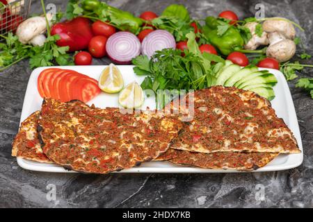 Türkische Lahmacun- oder türkische Pizza mit Tomaten, Petersilie und Zitrone auf Marmortisch Stockfoto