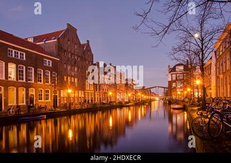 Leiden, Niederlande, 16. Dezember 2021: Blick entlang des Oude Rijn-Kanals (der alte Rhein), gesäumt von Ziegelhäusern, Bäumen und Fahrrädern in der blauen Stunde Stockfoto