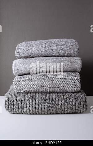Warmer, grauer Strickpullover auf weißem Tisch und grauem Hintergrund. Texturdetails für die kalte Herbstsaison Stockfoto